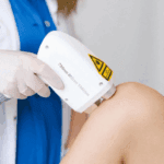 Doctor administering laser therapy session to patient's knee.