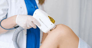 Doctor administering laser therapy session to patient's knee.